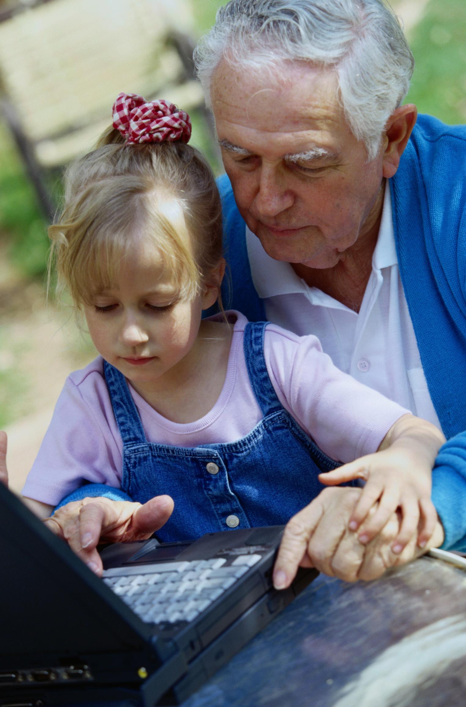 grandfather and granddaughter playing on a laptop